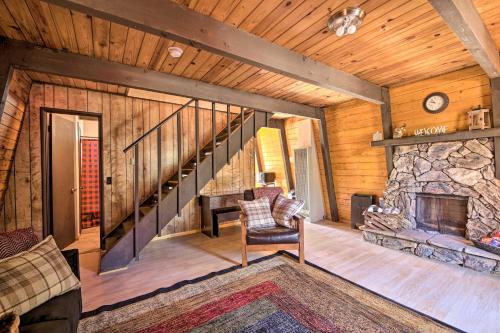 a living room with a staircase and a stone fireplace at Log Cabin Retreat with Deck Near Big Bear Lake! in Big Bear City