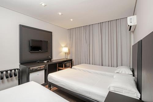 a hotel room with two beds and a flat screen tv at Slaviero Baia Norte Florianópolis in Florianópolis