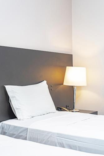 a bed with a white pillow and a lamp at Slaviero Baia Norte Florianópolis in Florianópolis