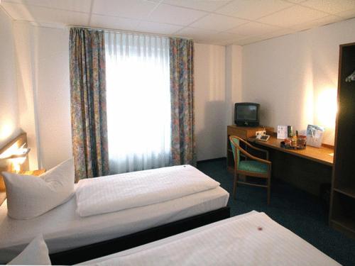 a hotel room with two beds and a desk and a window at Center Hotel Drive Inn in Hirschaid