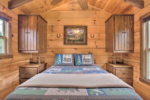 a bedroom with a bed with wooden walls and windows at Cabin in Mill Spring Near Parker-Binns Winery in Mill Spring