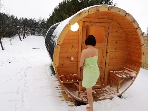 a woman in a green dress standing outside of a sauna at Siedlisko Bolek in Nadrybie