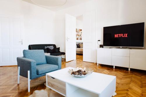 uma sala de estar com uma televisão e uma cadeira azul em Huge Central Designer Loft with Tyrolean Touch , 160m2 em Innsbruck