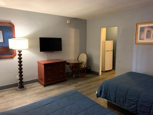 a hotel room with a bed and a desk with a television at City Center Motel in Las Vegas
