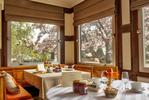 a dining room with two tables and two windows at Bleu Minuit L'Arche in Obersteinbach