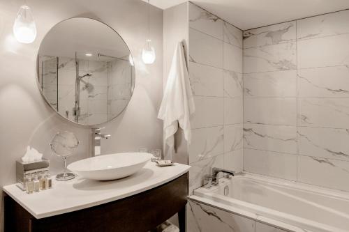 a bathroom with a sink and a tub and a mirror at Saint-Sulpice Montréal in Montréal