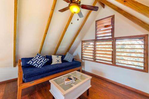 a living room with a blue couch and a window at Inn The Trees Cabañas in Placencia Village