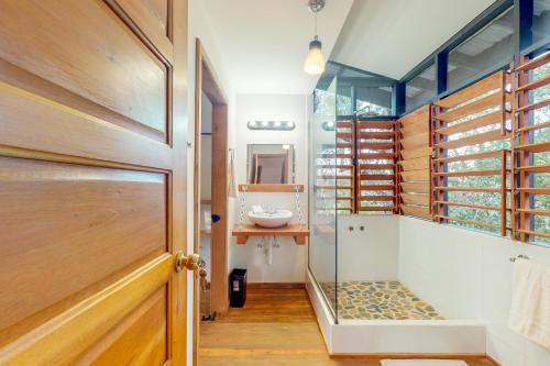 a bathroom with a sink and a glass door at Inn The Trees Cabañas in Placencia Village