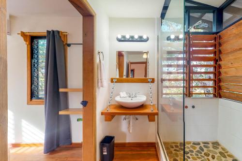 a bathroom with a sink and a glass shower at Inn The Trees Cabañas in Placencia Village