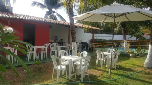 a group of chairs and an umbrella in front of a house at Pousada Res. Belmont in Pirangi do Norte