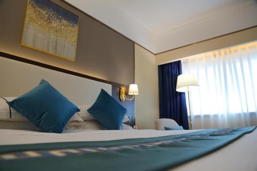 a hotel room with a bed with blue pillows at Asia International Hotel Guangdong in Guangzhou