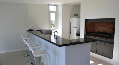 a kitchen with a counter with stools and a refrigerator at Arenas del Mar in Punta del Este