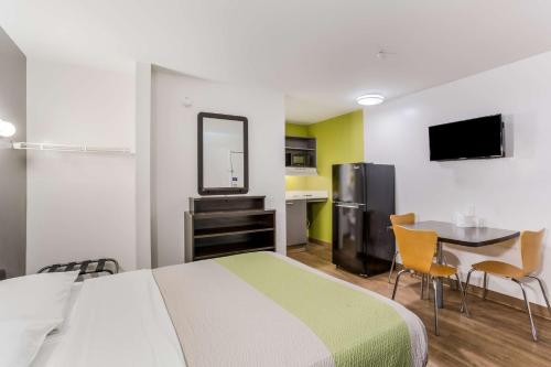 a hotel room with a bed and a table and a kitchen at Studio 6 Extended Stay - Jacksonville, FL - South in Sunbeam