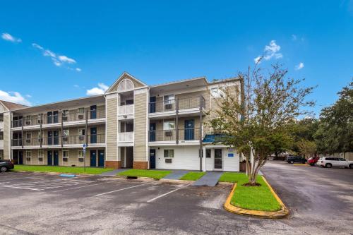 an apartment building with a tree in a parking lot at Motel 6-Jacksonville, FL - South in Sunbeam