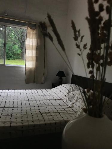 a bedroom with a bed and a vase with flowers at la vidurria -rre in Piriápolis