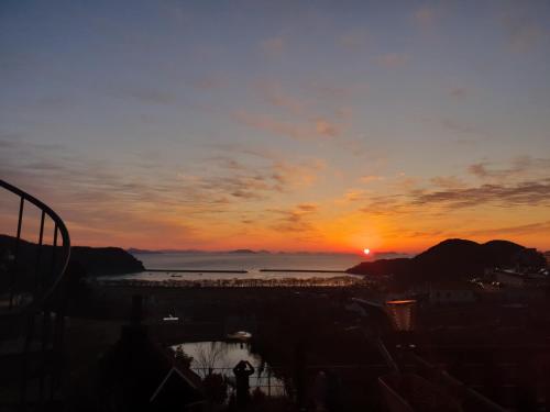 a sunset over the water with the sun in the sky at Namhae Neuhaus in Namhae