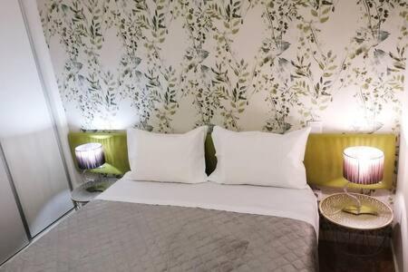 a bedroom with a bed with two lamps and a wall at Cativo Flat in Porto
