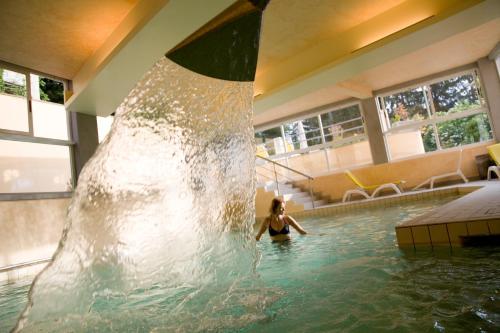 Eine Frau in einem Schwimmbad mit Wasserfall. in der Unterkunft Hotel & Terme Bagni di Lucca in Bagni di Lucca