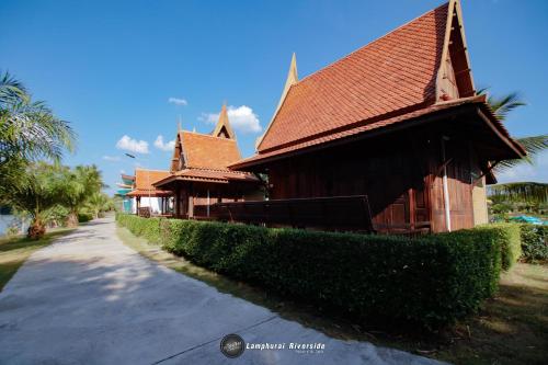 a building with a house with a hedge next to a road at Lamphurai Riverside Resort and Spa in Trat