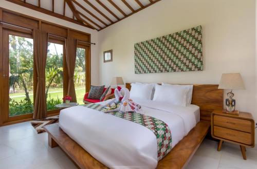 a bedroom with a large white bed and a window at Villa Ronggo Mayang at Balian beach in Antasari
