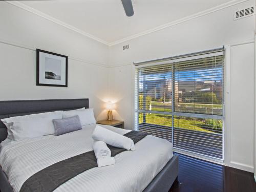 a bedroom with a bed and a large window at Driftwood House in Port Fairy