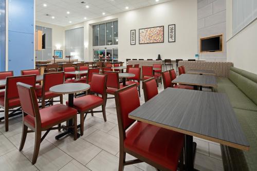 Un comedor con mesas y sillas rojas. en Holiday Inn Express Seattle - Sea-Tac Airport by IHG, en SeaTac