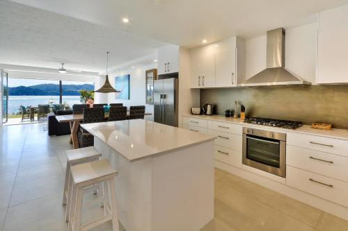 a kitchen with white cabinets and a view of the ocean at Hamilton Island Holiday Homes in Hamilton Island