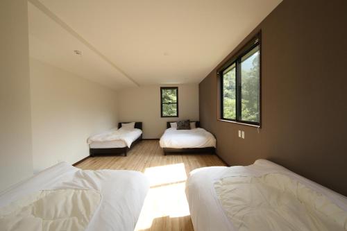 une chambre avec deux lits et deux fenêtres dans l'établissement Riner Stone, à Minakami