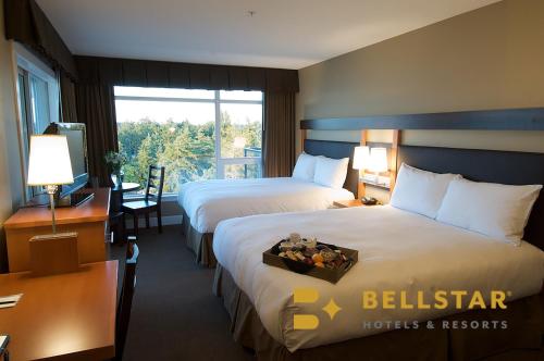 a hotel room with two beds and a window at The Beach Club Resort — Bellstar Hotels & Resorts in Parksville