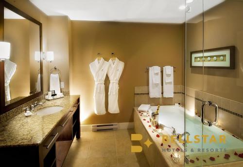 een badkamer met een bad, een wastafel en een bad bij The Beach Club Resort — Bellstar Hotels & Resorts in Parksville