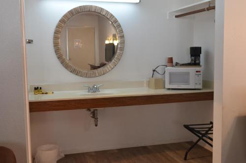 a bathroom sink with a mirror and a microwave at The Oak Motel in La Grange