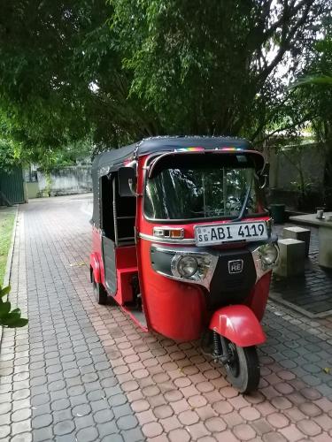 a small red and black vehicle parked on a sidewalk at Green Land Guest House in Pinnawala