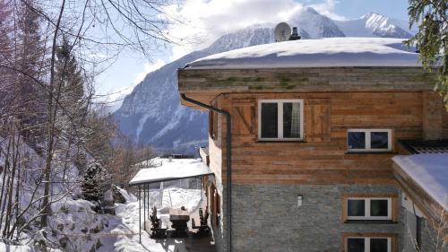 a building with a snow covered roof with a mountain in the background at Ferienhaus Skiblume in Oetz