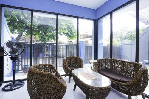 a room with chairs and a table and a fan at RedDoorz Plus Syariah At Lotus Hotel Bojonegoro in Bojonegoro