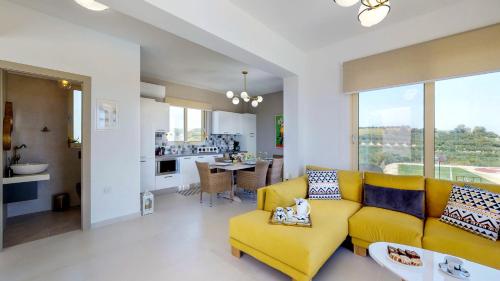 a living room with a yellow couch and a kitchen at Liberty & Freedom Luxury Villas in Platanias