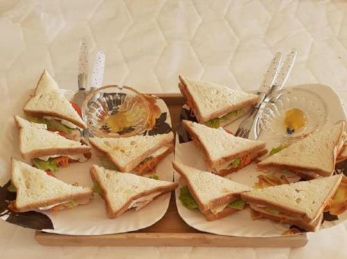 twee borden sandwiches op een dienblad met keukengerei bij WoodyCrest in Trincomalee