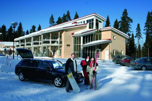 three people standing in front of a building with a snowboard at Spa Hotel Rauhalahti in Kuopio