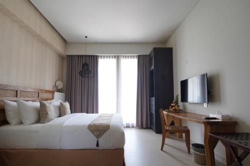 a bedroom with a bed and a desk and a television at Umah Tirta in Ubud