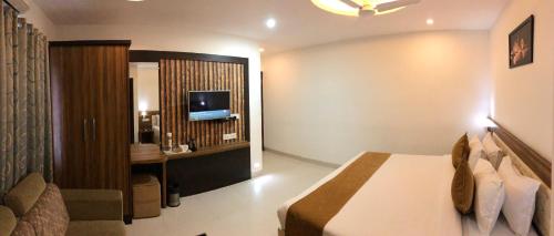 a hotel room with a bed and a television at The Porch Inn Hotel/Service Apartments in Bengaluru