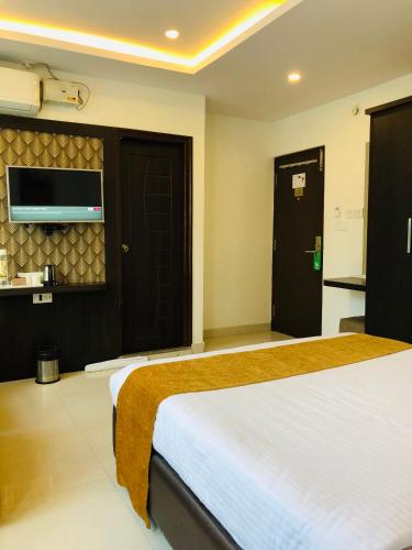 a hotel room with a bed and a flat screen tv at The Porch Inn Hotel/Service Apartments in Bengaluru