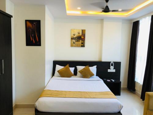 a bedroom with a large bed with yellow pillows at The Porch Inn Hotel/Service Apartments in Bengaluru