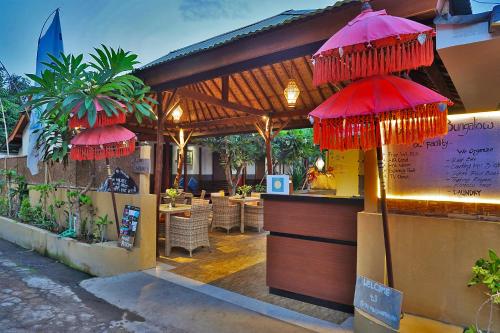 a restaurant with a bar with red umbrellas at Sari Gili Bungalow in Gili Air