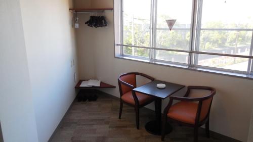a small table and two chairs in a room with a window at Kuretake Inn Gotemba Inter Gold Cabin in Gotemba