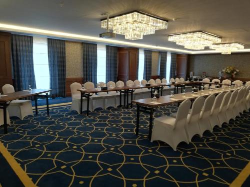 a conference room with tables and chairs and chandeliers at Hyksos Hotel in Erbil
