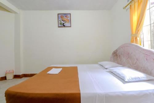 a white bed in a room with a window at Hotel Kayu Manis in Kaliurang
