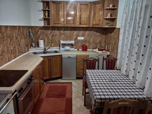 a kitchen with wooden cabinets and a table and a sink at Apartman KALJEVIĆ in Žabljak