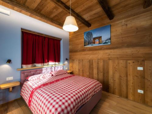 a bedroom with wooden walls and a bed with a red blanket at Agriturismo Gli Elfi in Aosta