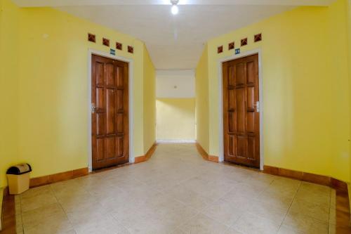 an empty room with two doors and a tile floor at Hotel Kayu Manis in Kaliurang