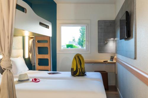una habitación de hotel con 2 camas y una mochila en la cama en ibis budget Berck Sur Mer en Berck-sur-Mer