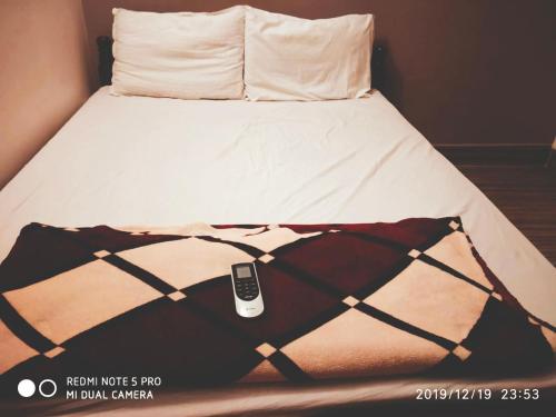 a bed with a cell phone sitting on top of it at Sai Baba Service Apartments in Chennai